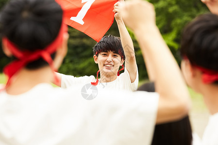 拿着旗帜男孩高中生们参加学校运动会背景