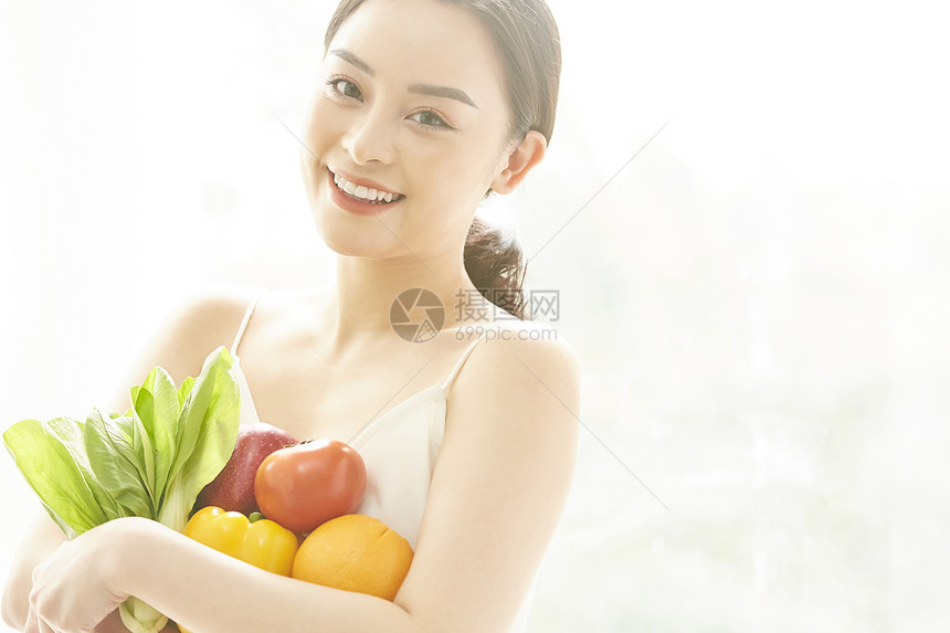 抱着一堆蔬菜微笑的年轻女子图片