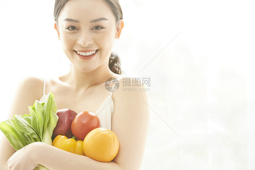 捧着蔬果微笑的年轻女子图片