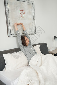 在床上伸懒腰的居家女性图片