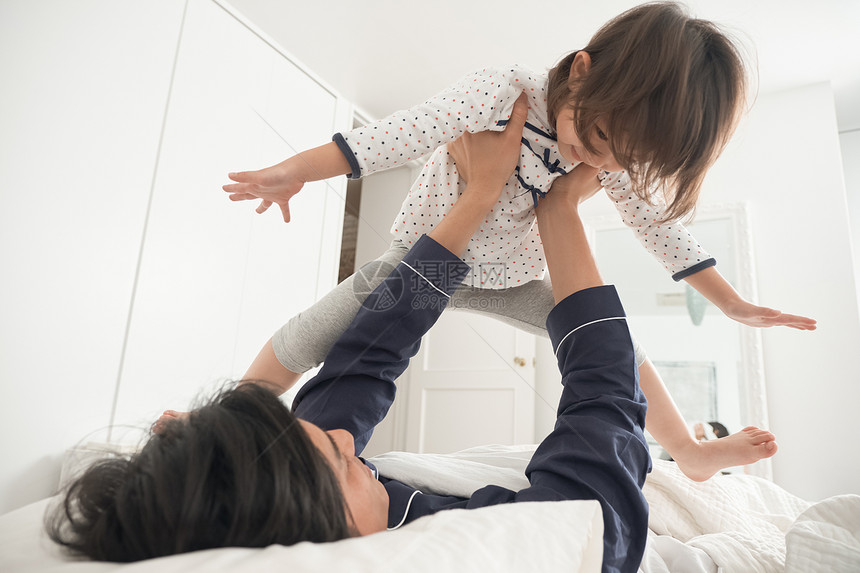 笑容房屋男父母和孩子在床上玩图片