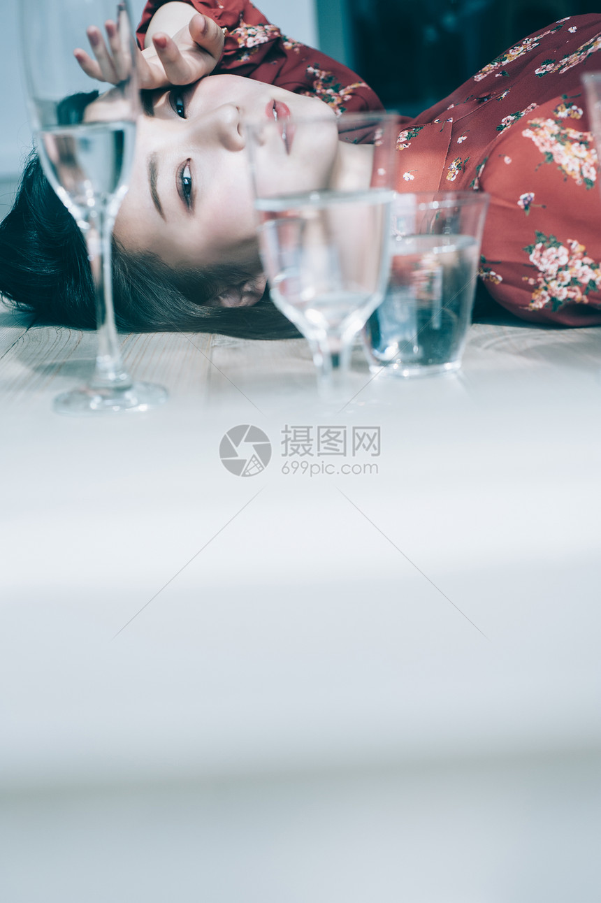 亚洲人女人连衣裙一杯水和红色的一件躺在地板上图片