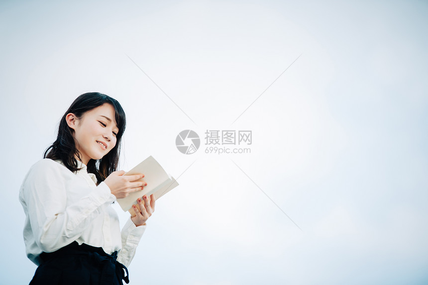 一件白色衬衣的一名妇女读书的在屋顶图片