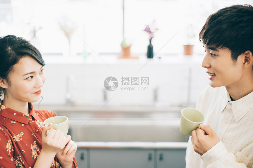 女孩恋人30多岁男和女与一个杯子聊天在厨房里图片