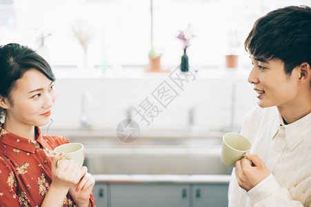 女孩恋人30多岁男和女与一个杯子聊天在厨房里图片