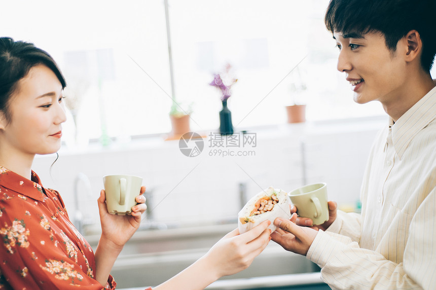 年轻情侣在厨房里递给对方三明治图片