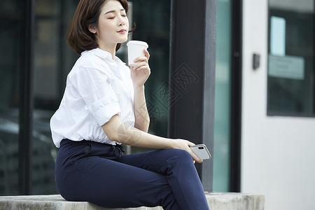 坐在台阶上的喝咖啡的女孩图片