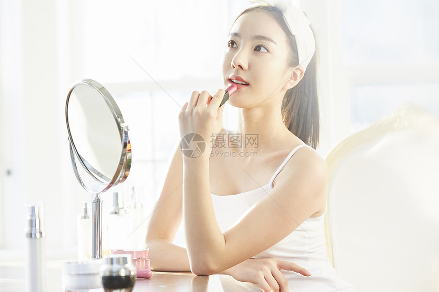 化妆使用口红的年轻女子图片