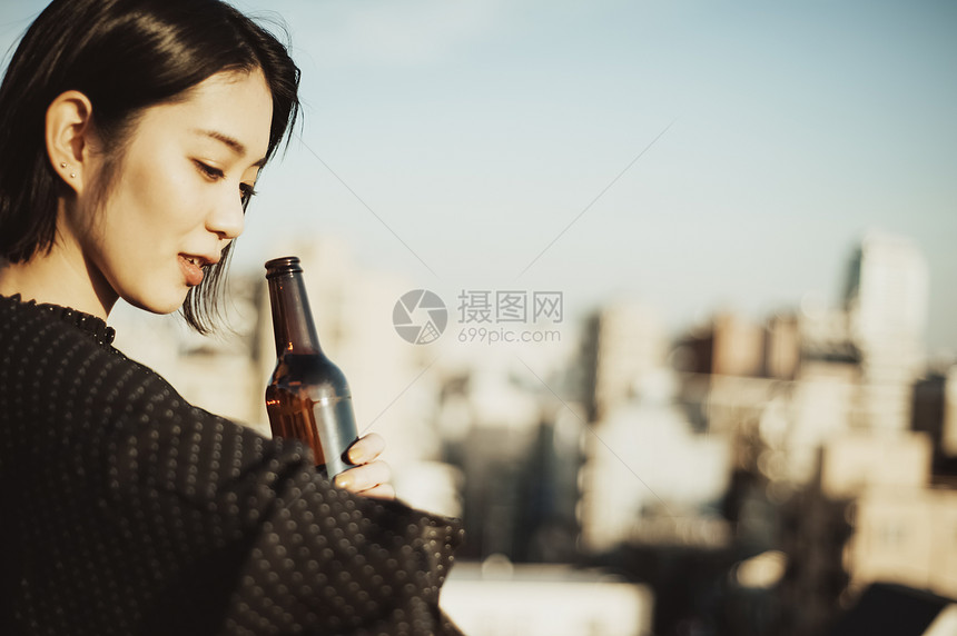 户外阳台边沐浴着夕阳喝酒的女性图片