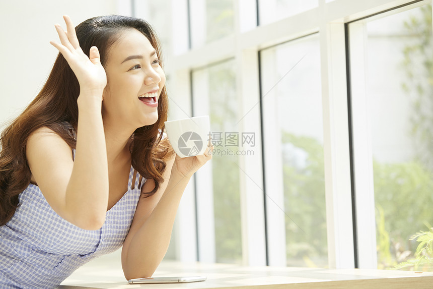 看向窗外打招呼微笑的年轻女子图片