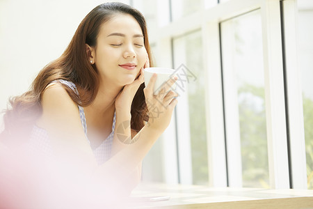 捧着咖啡闭眼微笑的年轻女子图片