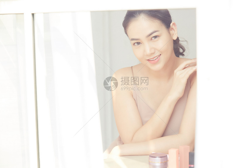 坐在镜子前美容护肤的年轻女性图片