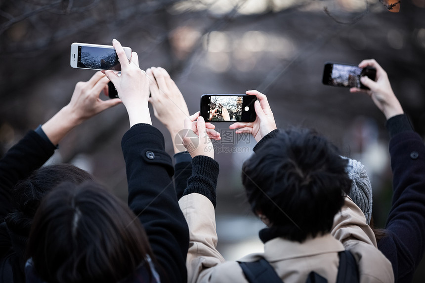 年轻人户外用智能手机拍照图片