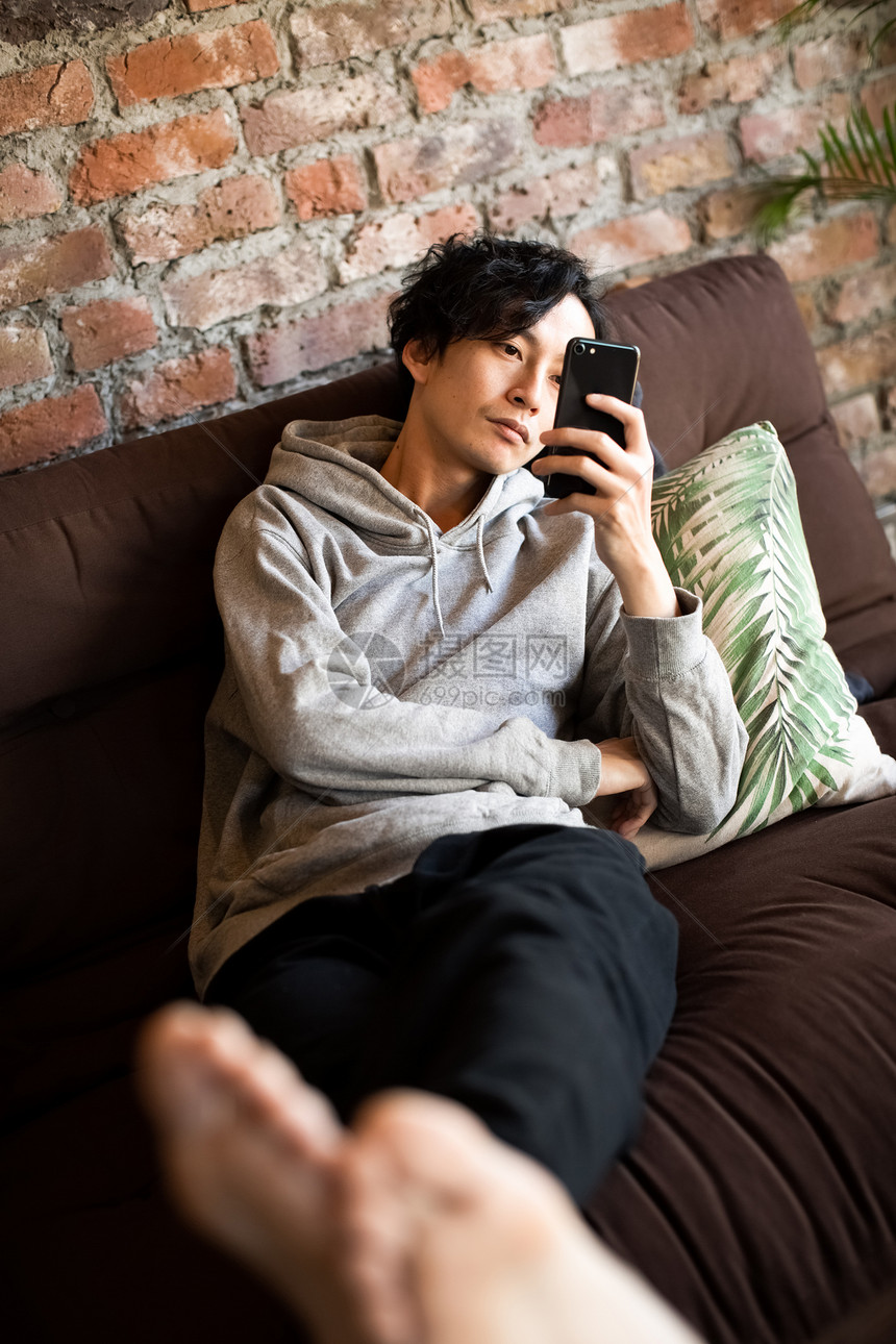 沙发上玩手机的成年男子图片