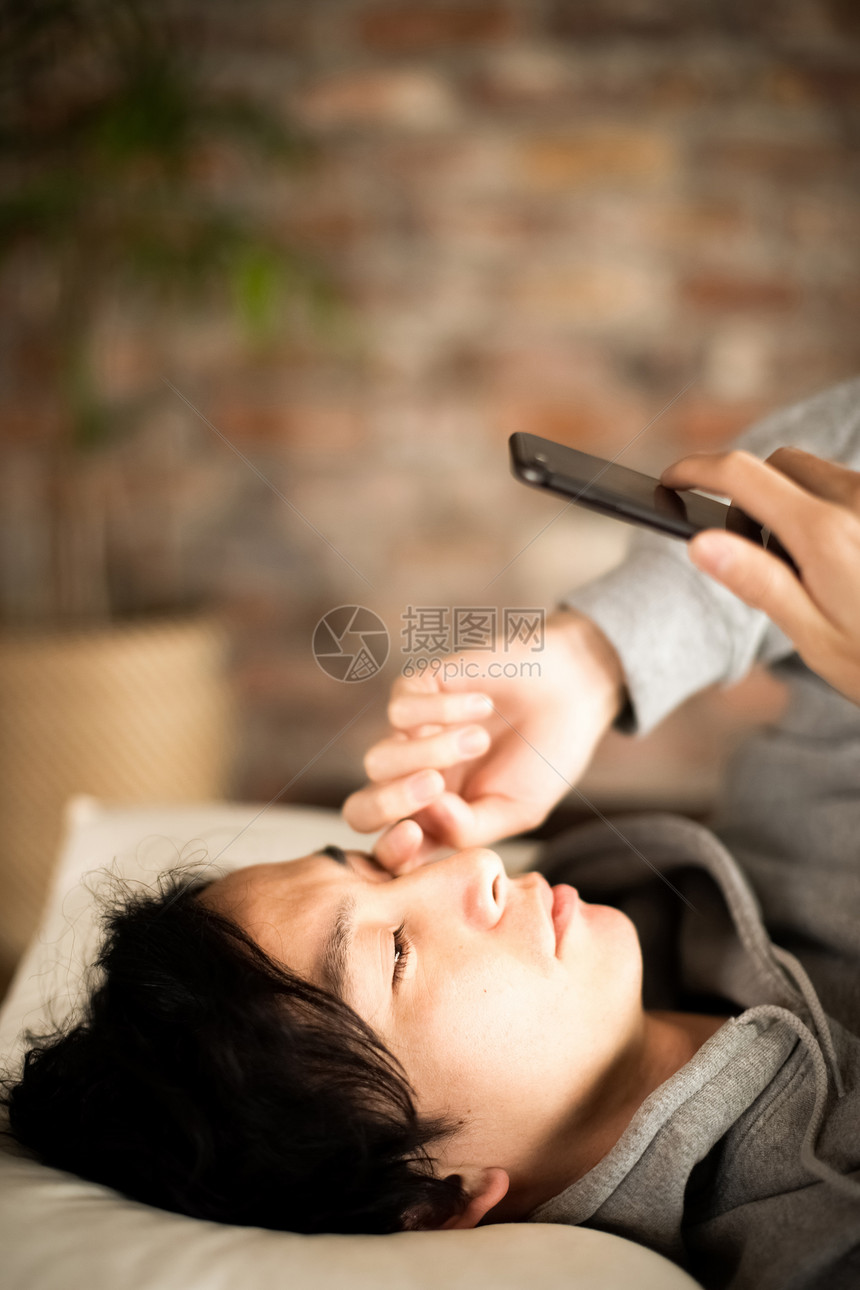 男人躺着看智能手机生活方式图片