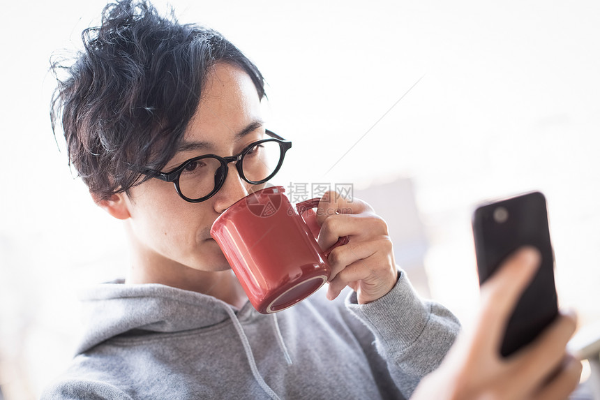 男人看着智能手机喝咖啡图片