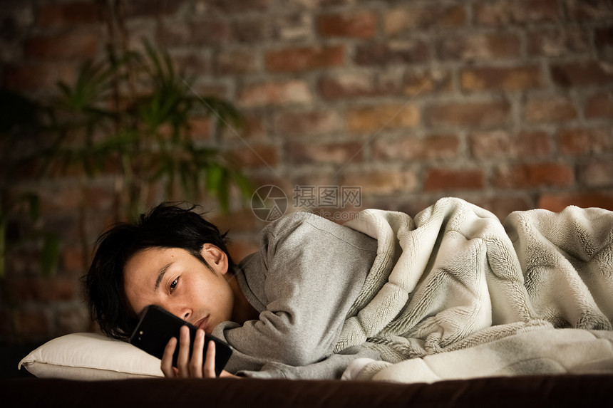 男人躺看着智能手机生活方式图片