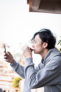 阳台上看手机听歌喝咖啡的男子图片