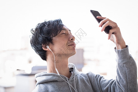 阳台上看手机听歌的男子图片