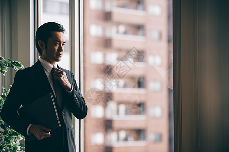 材料雇员男站立与文件的上司人在窗口旁边图片