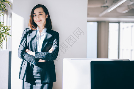 雇员女单人倾斜在柱子的微笑的妇女在办公室图片
