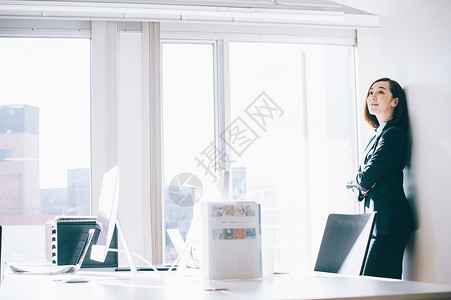 亚洲年轻女文职倾斜在柱子的微笑的妇女在办公室图片