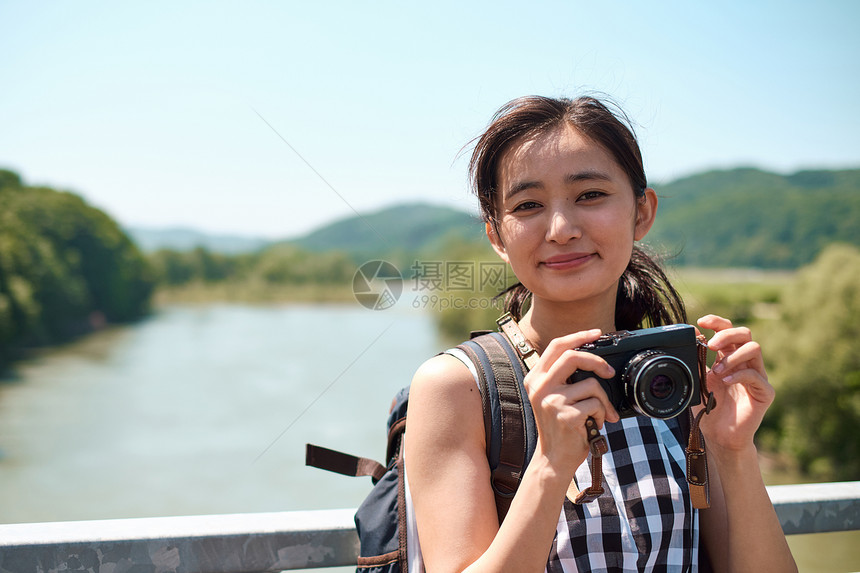 户外旅游拿着相机拍照的女青年图片