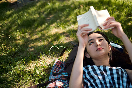 躺在草坪上阅读的女青年图片