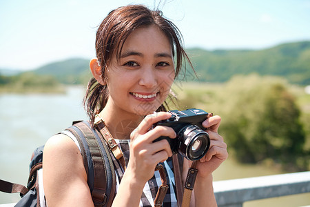 户外旅游拿着相机的年轻女子图片