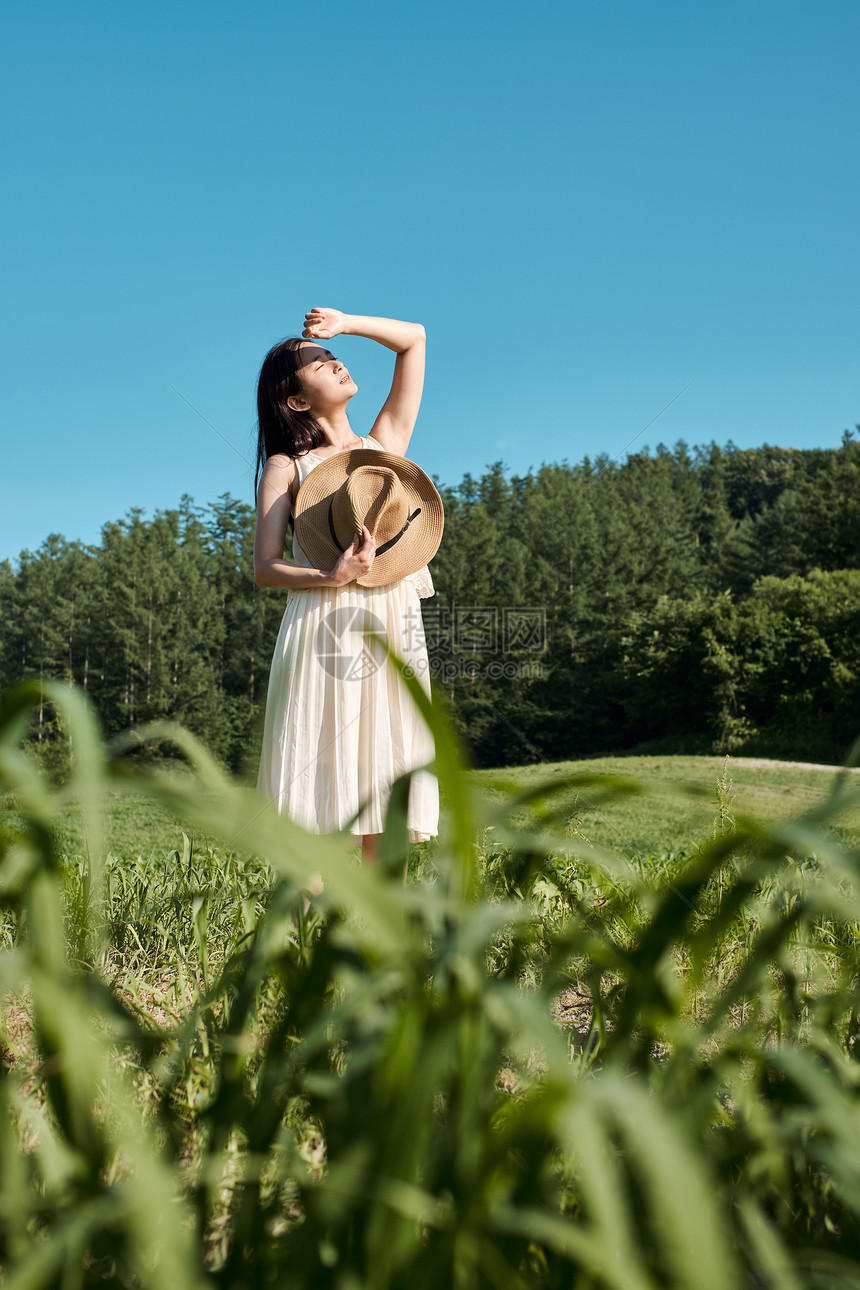 户外草坪拿着草帽的年轻女子图片