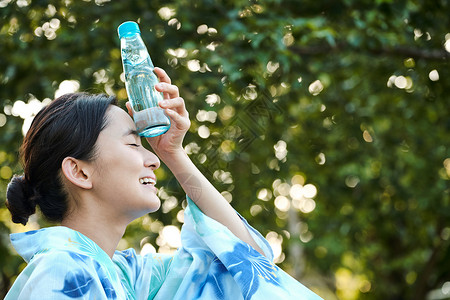 夏季拿着水杯额头降温的年轻女子图片