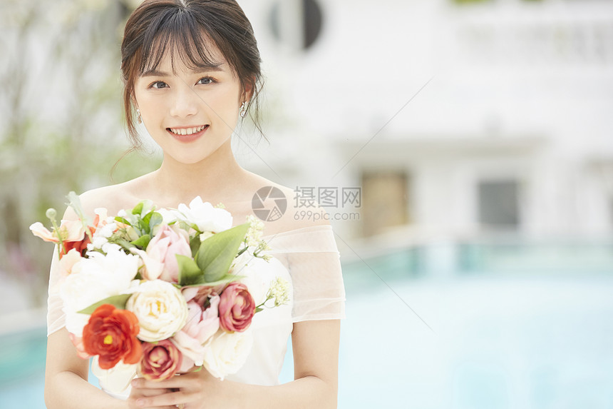 室外泳池边手拿捧花的新娘图片