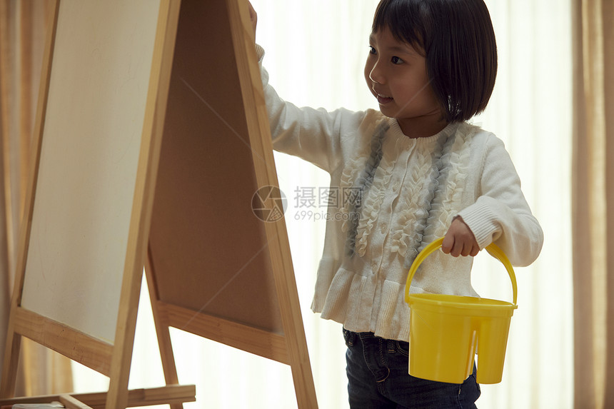 孩子气的较年轻青年去画架的女孩在客厅图片