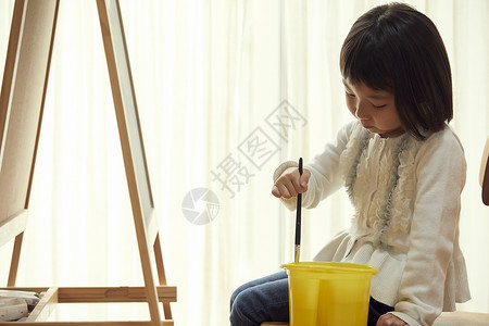 全年无休岁幼儿园资历坐在画架前面的女孩在客厅背景