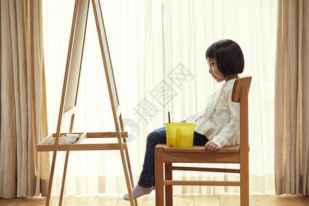 孤独的5岁全身照坐在画架前面的女孩在客厅图片
