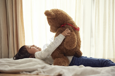 学前班儿童室内打盹睡觉与一头大熊的女孩在床上图片