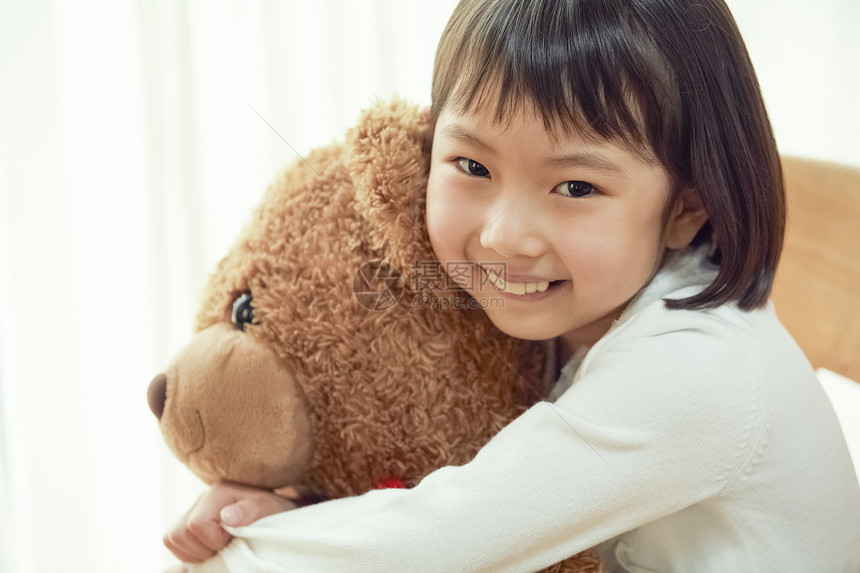 三岁儿童笑容使用与一头大熊的女孩坐椅子图片