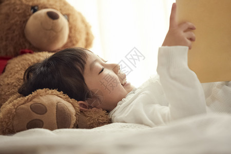 枕头画册孩子气的学前班3岁读在一个枕头的女孩一本画书有一头大熊的在床上背景
