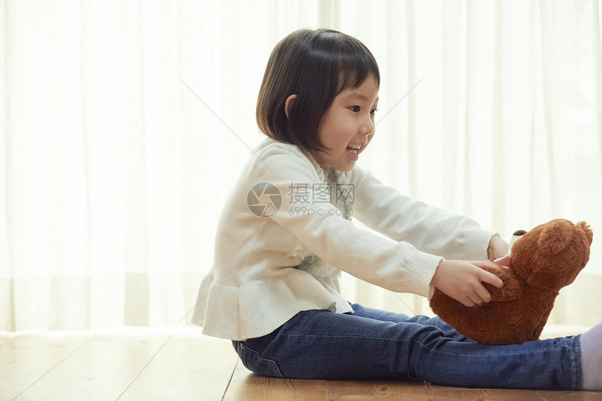 室内抱玩具熊的女孩图片