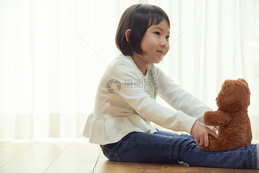 室内抱玩具熊的女孩图片