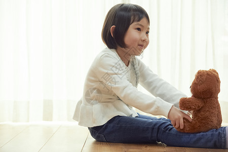 室内抱玩具熊的女孩图片