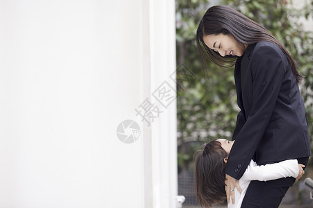 在房子外拥抱的母亲和女儿图片