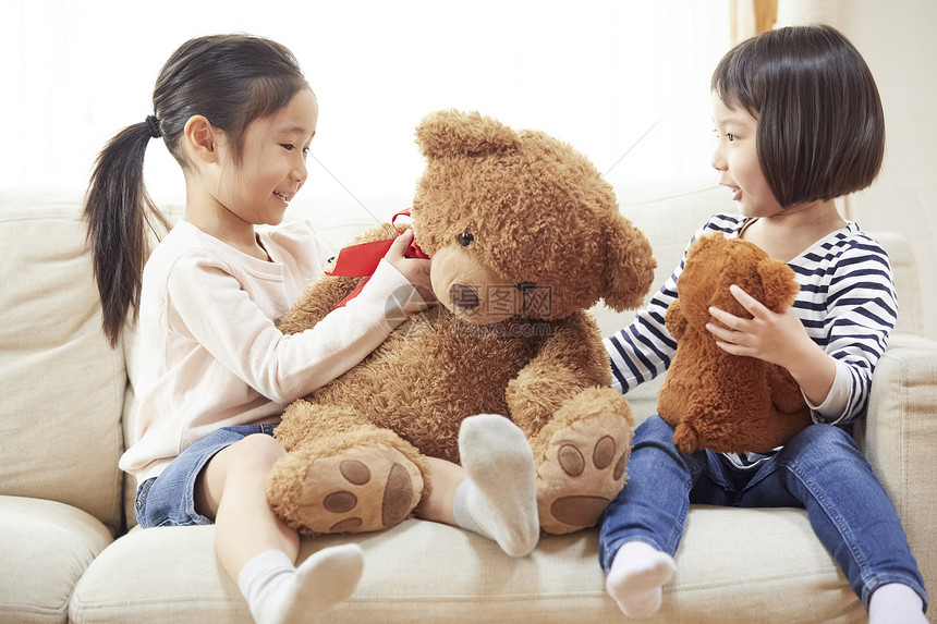 可爱五岁大人类姐妹们在沙发上玩大熊图片