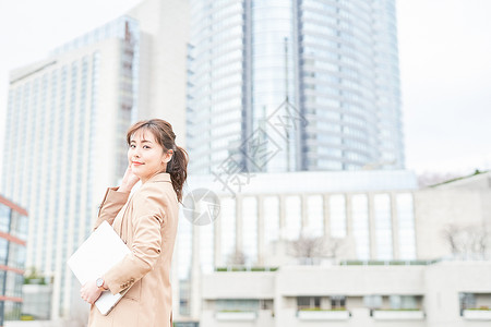 抱着笔记本电脑打电话的青年女性图片