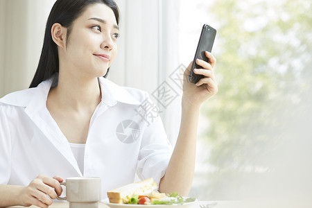 早餐拿着手机的年轻女子图片