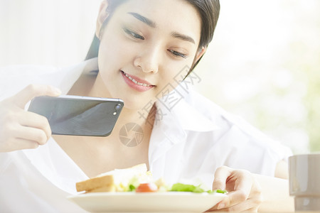 拿手机拍食物的居家女孩图片