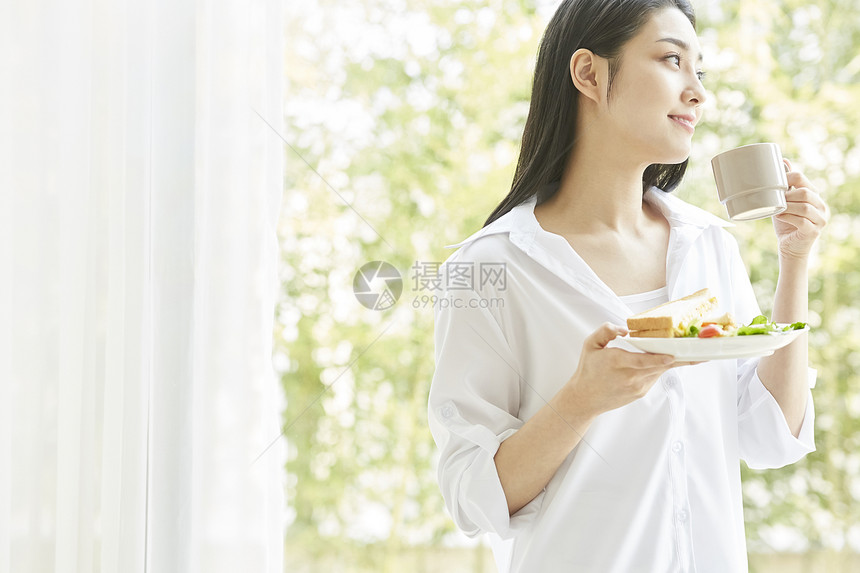 手拿茶杯和食物的年轻女孩图片