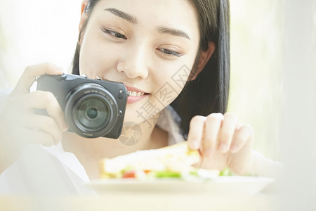 拿相机拍食物的居家女孩图片