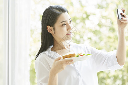 拿手机拍食物的居家女孩图片