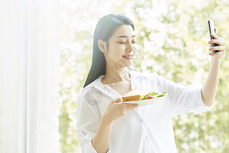 拿手机拍食物的居家女孩图片